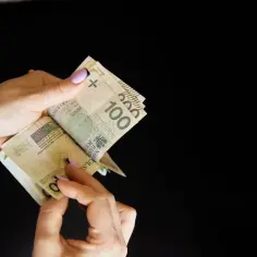 Dłonie liczą banknoty 100 zł. Może to być związane ze zniesieniem współwłasności i podziałem majątku.