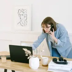 Wirtualna asystentka w okularach rozmawia przez telefon, pracując przy laptopie.