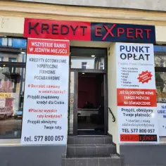 Tablica z napisem "KREDYT EXPERT" i ofertami kredytów oraz punktem opłat.