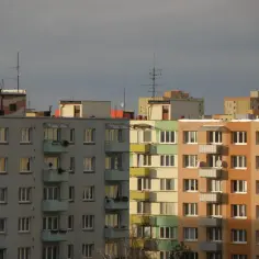 Bloki mieszkalne z balkonami, gdzie każdy lokator ma służebność mieszkania. Widok na wiele okien i kolorowe elewacje.