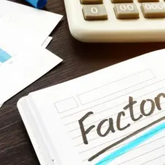 Notatnik z hasłem "factoring", obok kalkulator i wykresy.