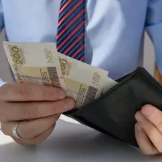 Mężczyzna w koszuli i krawacie wkłada banknoty 200 zł do portfela. Dba o swój cash flow.