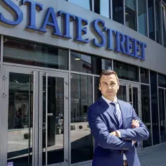 Mężczyzna w garniturze przed budynkiem z napisem "STATE STREET".
