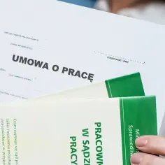 Umowa o pracę, która musi być na czas nieokreślony, leży obok broszury o sprawach pracowniczych.