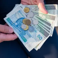 Dłonie trzymają polskie banknoty i monety. Ile razy można dać darowiznę dziecku? Zależy od kwoty i potrzeb.