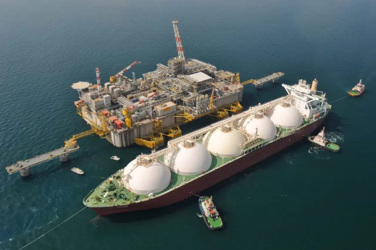 Okręt LNG przycumowany do platformy wydobywczej. Widać holowniki asystujące przy manewrach. To ciężka praca na statku.