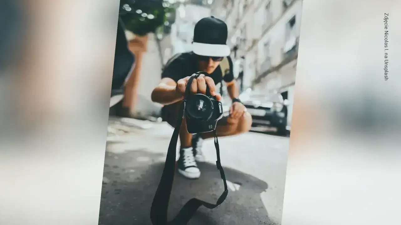 Młody fotograf w czapce z daszkiem trzyma aparat, zastanawiając się, ile zarabia fotograf.