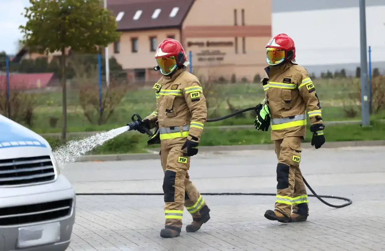 Strażak w akcji, z węża leje się woda. Zastanawiasz się, ile zarabia strażak? To praca pełna poświęcenia.
