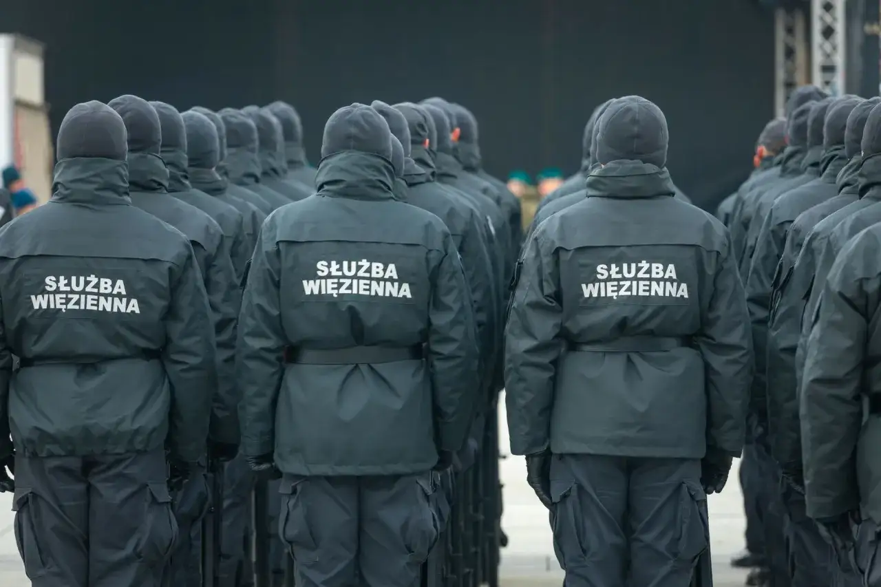 Służba więzienna zarobki - funkcjonariusze w mundurach stoją w szeregu.